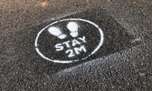 a social distancing sign stencilled on a pavement