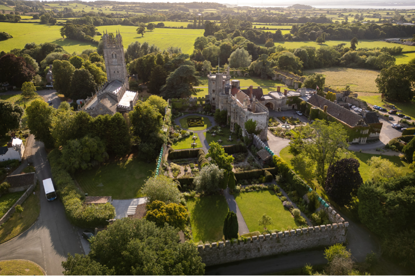 Aerial view of castle, castle walls, and grounds, surrounded by countryside.
