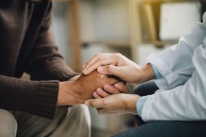 Close up of two people holding hands, comforting gesture